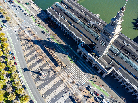 Aerial view of San Francisco ferry building during springtime day with the bay in background, just above Harry Bridges Plaza