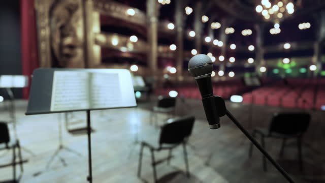 A microphone and a sheet music stand in front of a stage