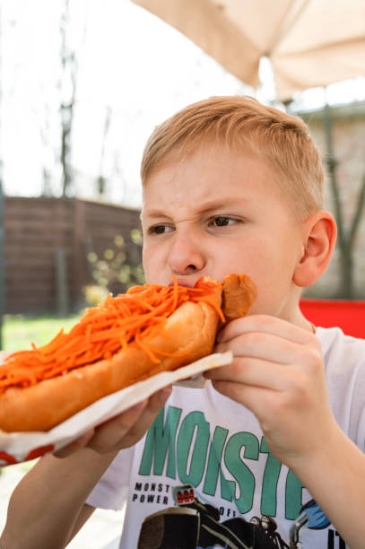 istock A boy eats a hotdog at a table in a cafe in a spring park 2148867581