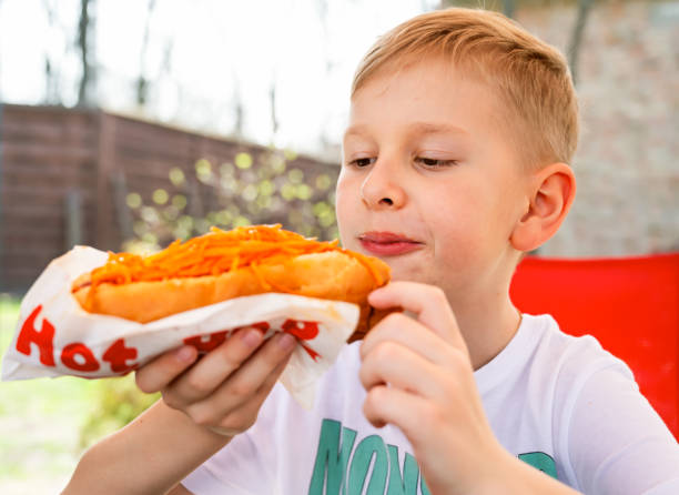istock A boy eats a hotdog at a table in a cafe in a spring park 2148867588