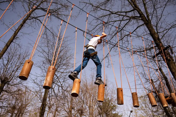 A boy in a helmet climbs a rope park in the spring