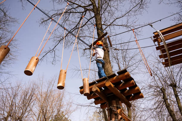 A boy in a helmet climbs a rope park in the spring