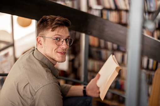 Young Male College Student Looking at Camera in Book Store