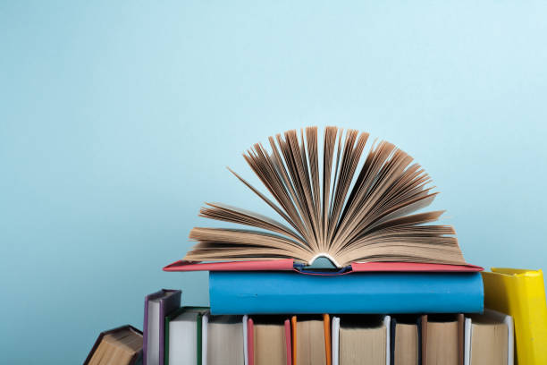 istock Book stacking. Open book, hardback books on wooden table and blue background. Back to school. Copy space for text. 2148869783