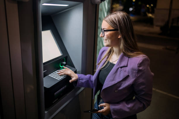 istock Single person in front of ATM at night entering PIN code on the machine 2148869961