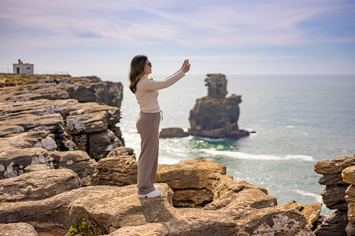 Tourist taking photos on the cliff in Peniche, Portugal