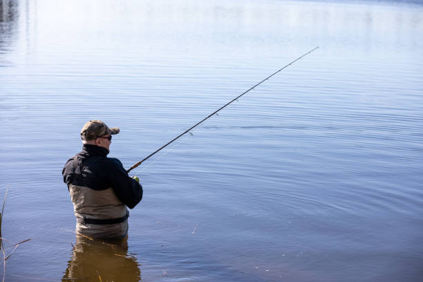 istock Fisherman in waders catches pike in the lake 2148871907