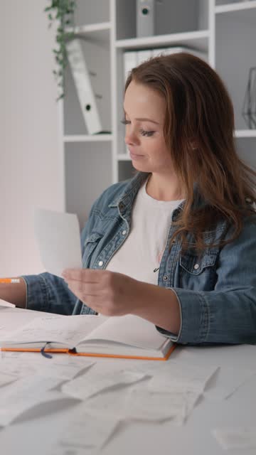 A woman dressed in casual clothes works at an accounting notebook. It calculates expenses, analyzes financial data and plans a budget for expenses, credit and deposit. Small Business