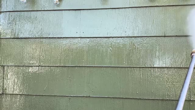 Power washing house siding in slow motion close up