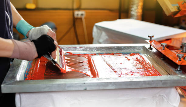 istock silk screen printing. male hand with a squeegee. serigraphy production. selective focus photo 2148872437