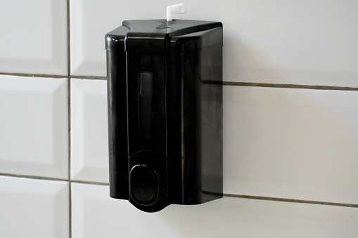 Soap dispenser hanging on bathroom tile wall