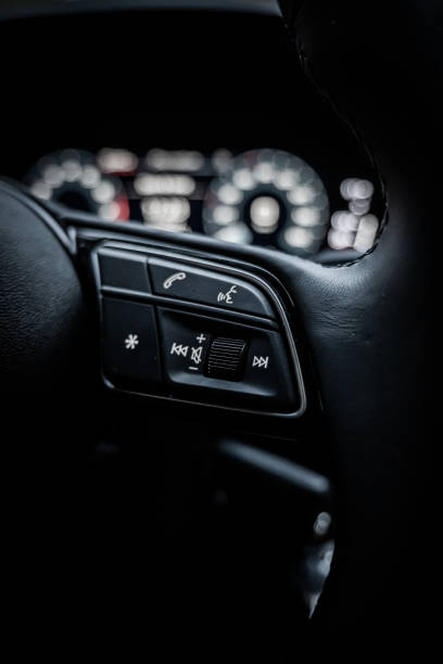 istock Car media buttons on steering wheel, volume, skip and phone buttons. Car dashboard in background. Dark, black. 2148873841
