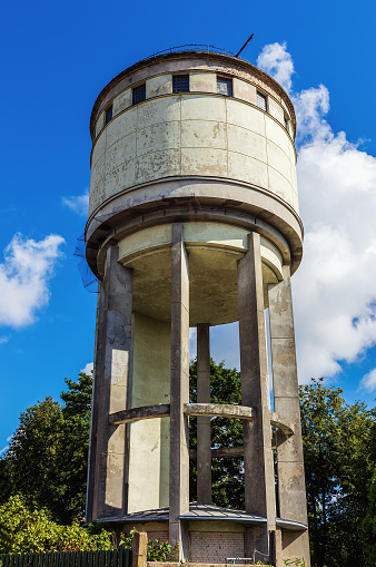 Old Soviet-era city water tower on a sunny summer day against the background of the sky. Panevezys. Lithuania. 16. 08. 2022.