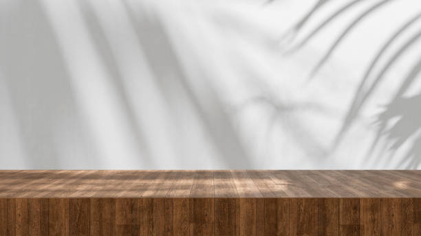 istock Wooden table high quality table top close up with soft palm shadows and sun light, summer background product display - empty copy space for product and design mock up, wooden countertop and white wall 2148874415