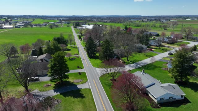 Quaint green Suburb of USA with single family houses at sunlight in spring. Countryside street of Pennsylvania with large farm houses. Aerial flyover shot.