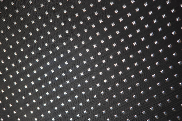 Background black textured surface with shiny metal squares evenly spaced on the surface