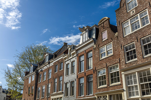 Dutch Amsterdam facades in the city center of Amsterdam on a spring day with blue sky. Typical brown brick facades
