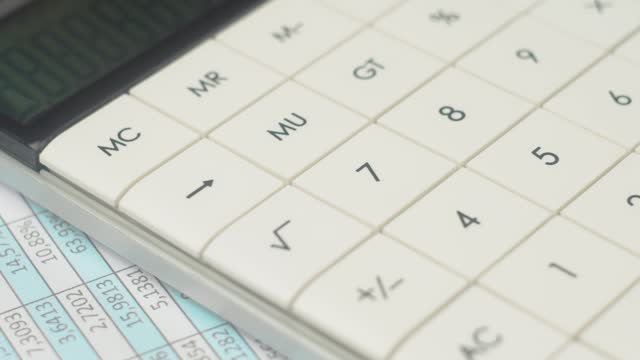 Use calculator calculates in spreadsheet incomes and expenses, pay for loan, entering data results, documents, invoices, utility bills lie on table, close up