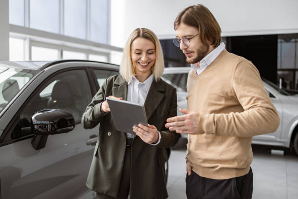 istock Confident saleswoman explaining all car features using tablet to handsome owner. 2148876313
