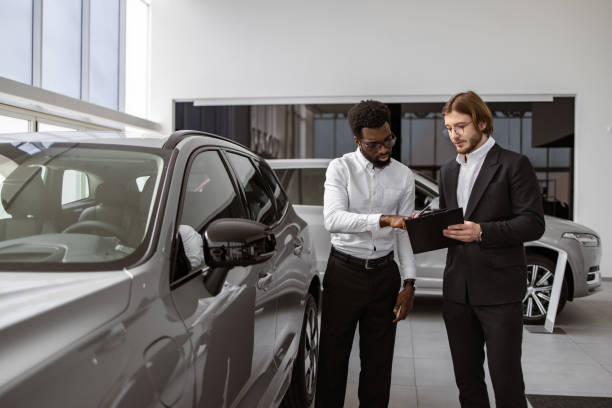 istock Caucasian salesman explaining all the car features using clipboard to owner. 2148876394