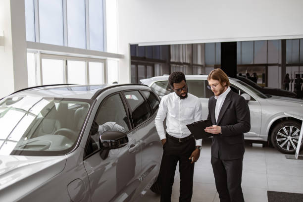 istock Caucasian salesman explaining all the car features using clipboard to owner. 2148876395