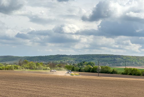 Tractor and field. Farm tractor with trailer seeder making sowing agricultural field. Process sowing plowed field. Agricultural machinery working on farming field