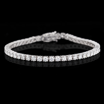 Beautiful gold bracelet made of white gold with diamonds on a black background close-up