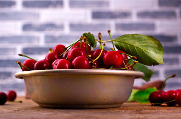 fresh cherry with leaves in metal bowl