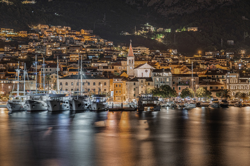 Boats moored at Makarska harbor and promenade at night, Croatia