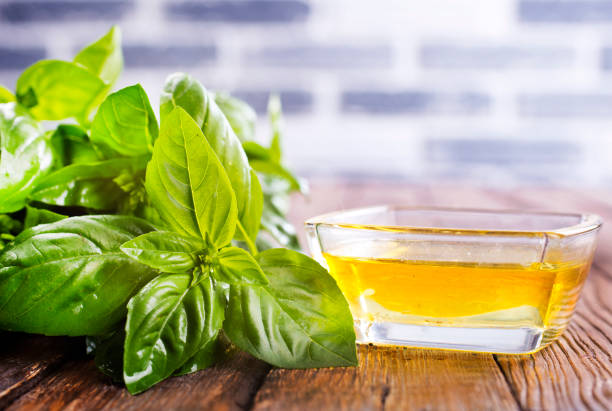 Basil oil in glass bowl and fresh herbs
