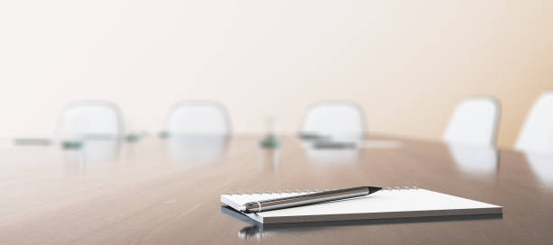 istock Close up of wooden conference table with empty notepad and pen for morning notes. Blurry chairs on wide backdrop . Business meeting concept. Mock up place, 3D Rendering. 2148882715