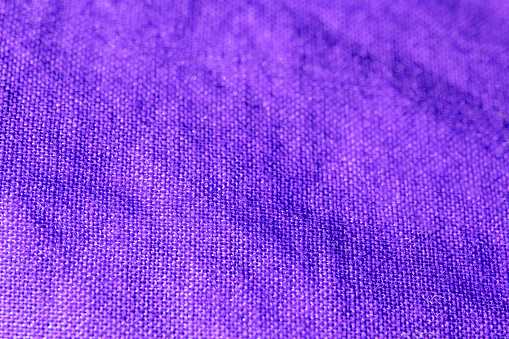 organic textured linen fabric background, purple colored fabric.