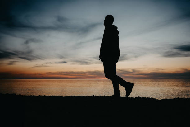 A person standing on th.e beach in golden sunset light
