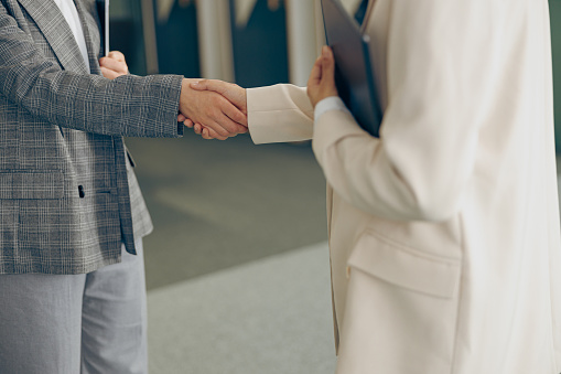 Close up of female executive manager is making successful deal with partner shaking hand at work