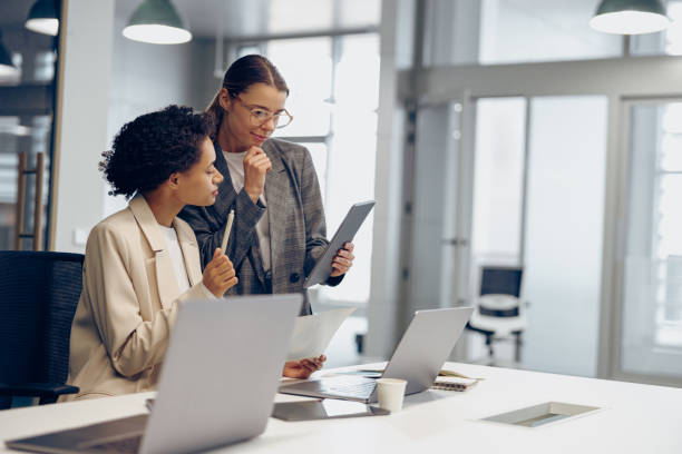 istock Stylish female executives managers discussing financial accounting papers and using digital tablet 2148887806