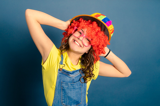 young girl cheerleader with multicolored hat, red wig and pink glasses