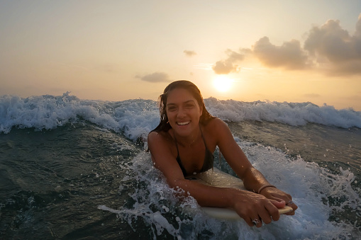 Woman Riding a Wave Lying Down on Surfboard