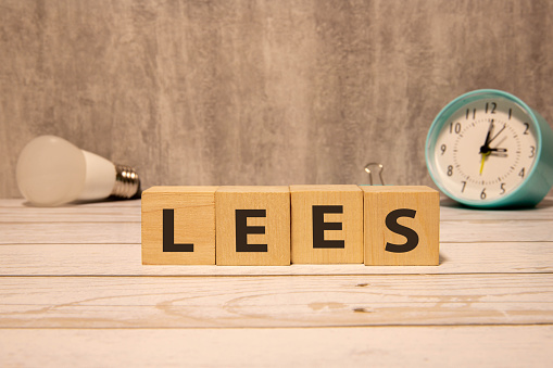 Having less stress or being stress-less. The word 'STRESS' and 'LESS' on wooden cubes. Male hand. Beautiful yellow table, white background, copy space.