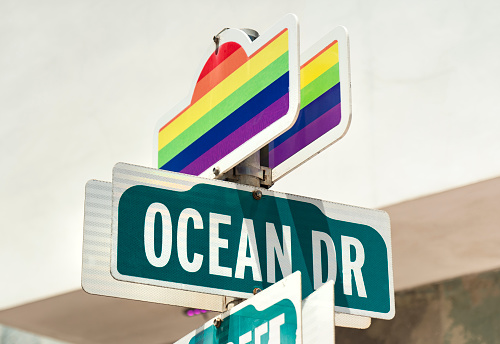 Pride flag colours and Miami Florida Ocean Beach road direction sign in South Beach