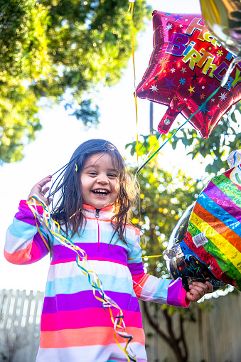 A cute little girl holding birthday balloons