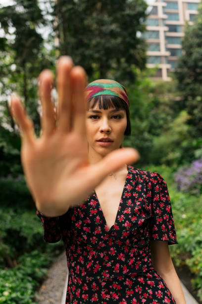 istock Young woman  showing stop gesture by hand while standing in park 2148893195