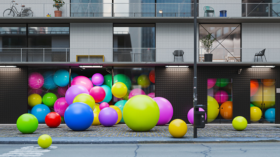 A surreal scene of multi colored balls falling out of the building.