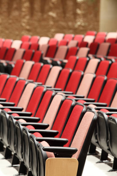 Rows of red, pink, and salmon colored theater seats in a modern theater.