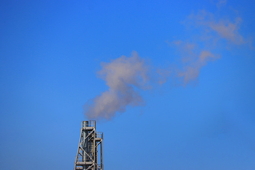 White smoke against blue sky, climate change. Factory smoke causes pollution in the air.