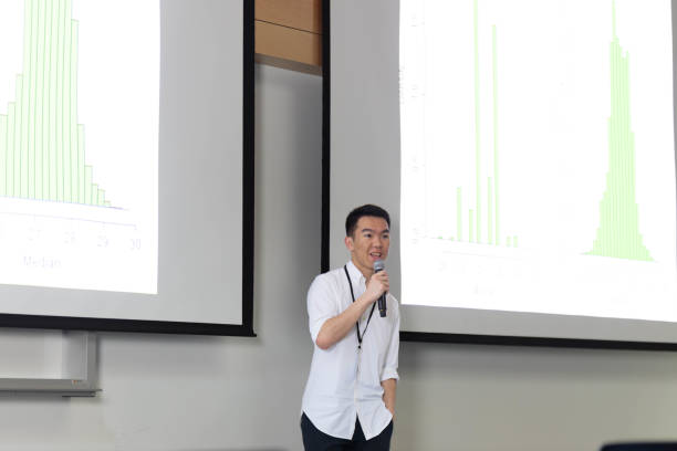 istock Young man presenting statistics in front of a projector screen holding a microphone 2148896406