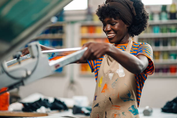 istock Happy interracial printing shop worker manipulating screen printing press 2148896500