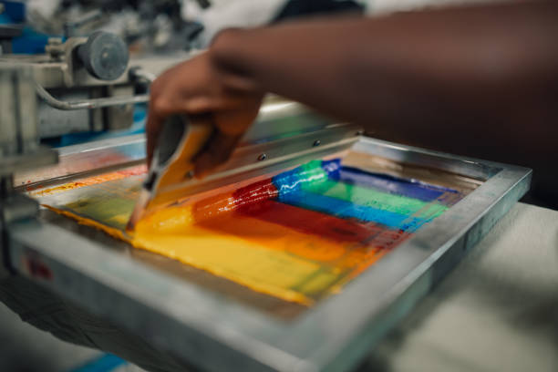 istock Close up of interracial press woman's hands silk screen printing. 2148896514