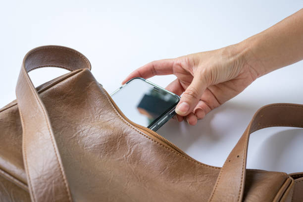 Woman put inside phone into brown leather handbag.