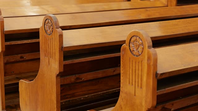 Slow track along rows of vintage wooden pews in Lutheran church.