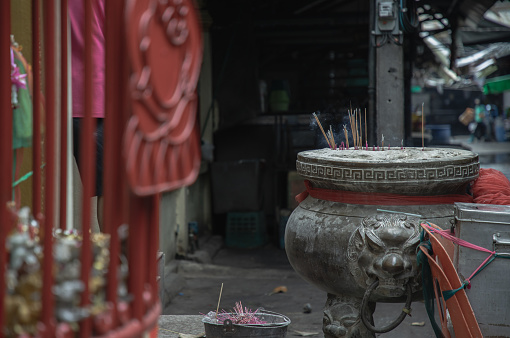 Bangkok, Thailand - Apr 11, 2024 - Incenses burned with white smoke on incense burner with dragons sculpture decorate in front of old shrine. Space for text, Selective focus.
